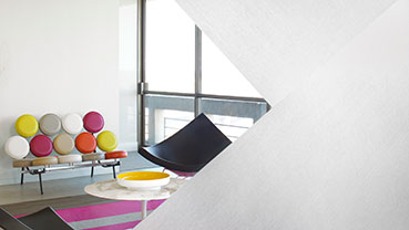 Modern office space with glass-walled meeting room featuring frosted film, plants, and exposed brick accents.